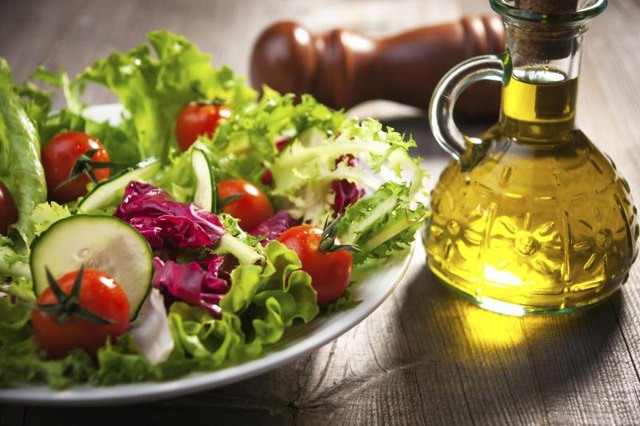 A jar of olive oil next to a salad