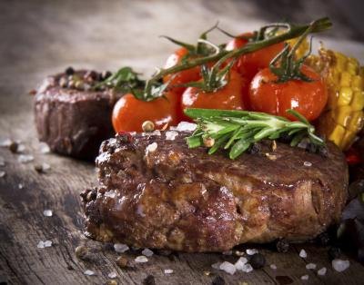 Grilled steak and tomatoes on a wooden table