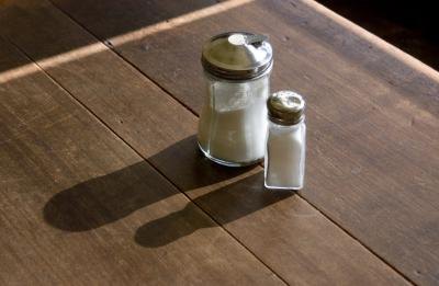 A sugar and salt shaker on a wood table