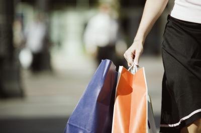 A woman walks and carries shopping bags.