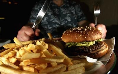 Man about to eat hamburger and plate of fries