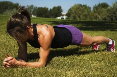 A woman doing a plank outside on grass