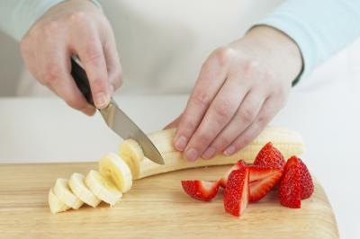 woman slicing strawberries and banana