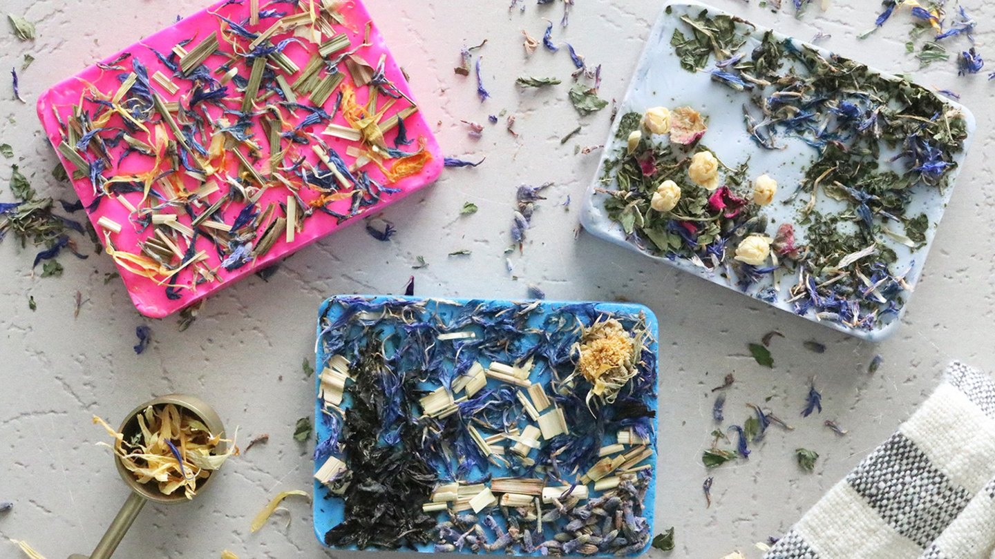 Three bars of soap covered in dried flowers and herb pieces
