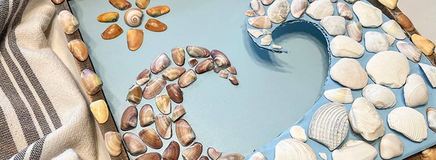 Seashell mosaic craft set against a beach towel 