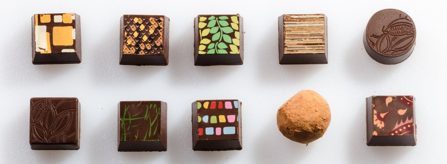 Ten assorted chocolate truffled with colorfully painted tops featuring traditional Ghanaian designs