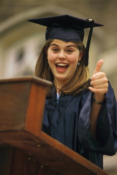 Young woman giving thumbs up at graduation speech