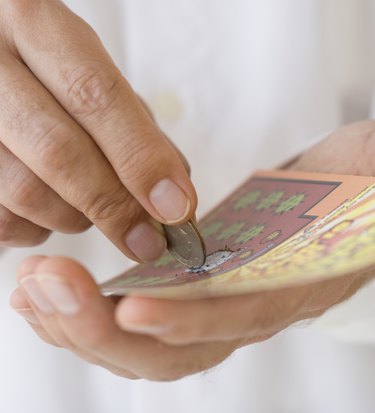 Man scratching lottery card with coin