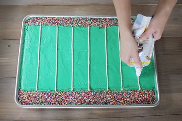 Piping lines of white icing to create football grid lines