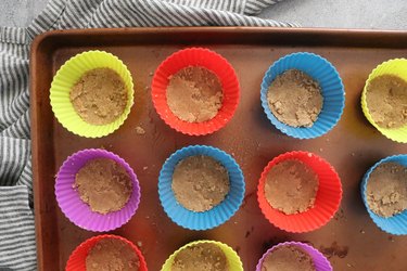 Pack graham cracker crumbs into cupcake liners.