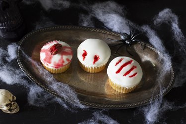 Three cupcakes decorated with zombie brain, vampire bite & monster claw