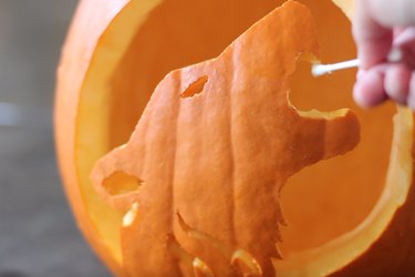 Rubbing petroleum jelly on carved edges of pumpkin