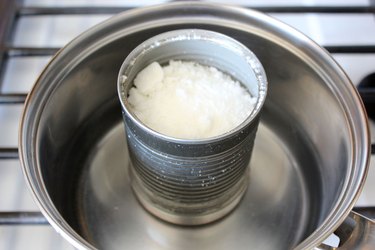 Crumbles of wax inside a tin can placed in a stovetop pan of water