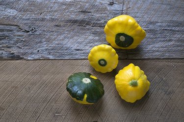 An overhead view of a random arrangement of four pattypan squash on a rustic wood surface