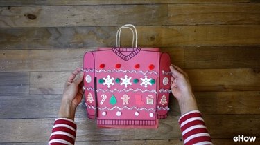 Attaching paper sweater to gift bag.