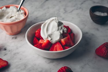 picture of a bowl of strawberries topped with dairy-free coconut whipped cream