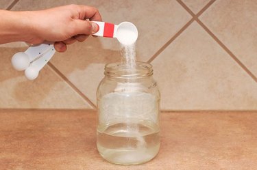 An image of baking soda being poured into a jar of water.
