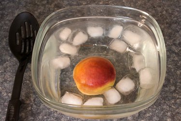 A peach in a bowl filled with ice water