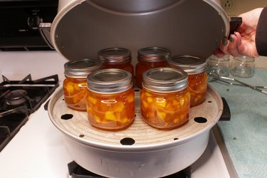 Jars of preserved homemade peach jam on a steamer canner