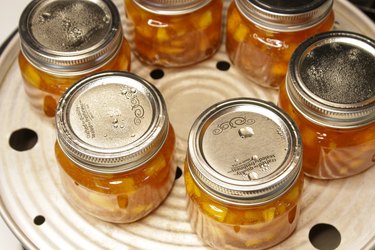 Jars of preserved homemade peach jam on a steamer canner