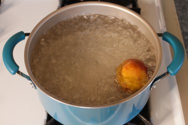 Peach inside a pot filled with boiling water