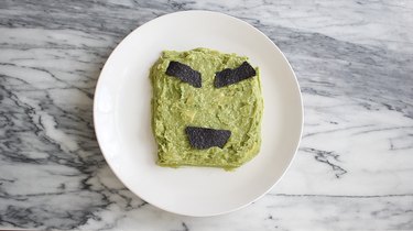 Guacamole in square shape with tortillas forming eyebrows and mouth