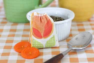 Hand-sewn tea bag with orange buttons on an orange-and-white checkered tablecloth