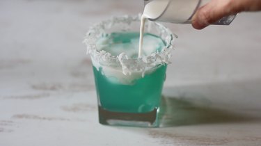Pouring coconut cream into cocktail