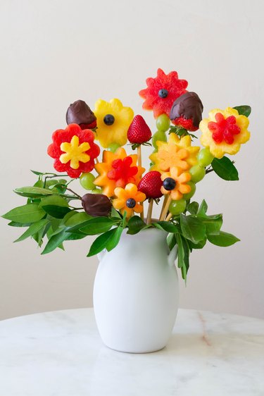 DIY edible fruit flower arrangement in white vase on table