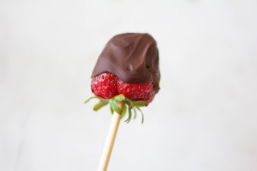 Wood skewer inserted into stem of chocolate-dipped strawberry