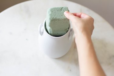 Pressing block of floral foam into vase