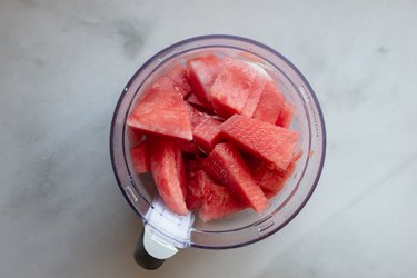 Cubes of watermelon placed within a food processor to make watermelon sorbet