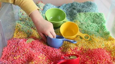 Child's hand explores an finished rainbow sensory box