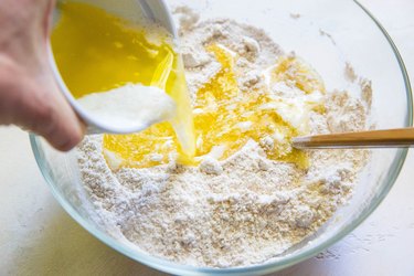 Butter pouring into mixing bowl with flour and sugar