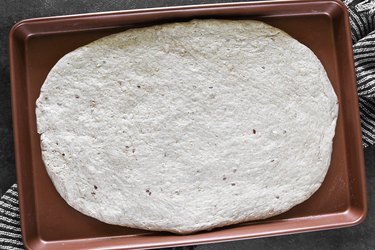 Spread pizza crust on baking sheet