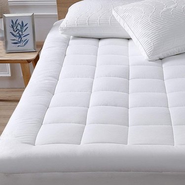 Twin XL mattress pillow topper on bed. It's tufted and looks very full and comfortable.