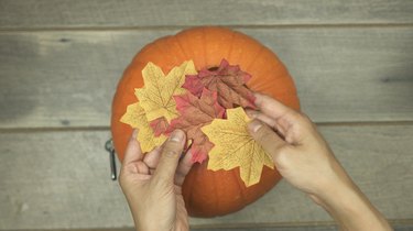 Decorating DIY Pumpkin Keg with fabric leaves