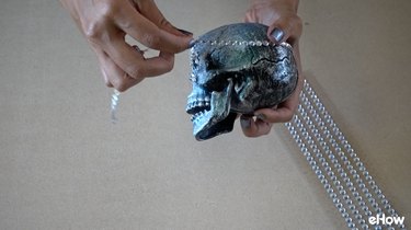 Applying gemstone strips to plastic skull for DIY Gemstone Studded Halloween Skull