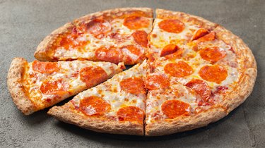 Sliced hot pepperoni pizza on a brown background.