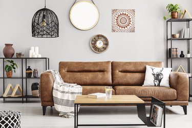 Warm ethno living room with big comfortable leather couch and metal furniture, real photo