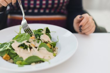 Pregnant woman eating fresh vegan salad at cafe