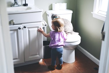 Girl and cat in bathroom.