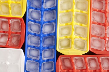 Full ice cube trays in bright-colored plastic, packed tightly together in an overhead view