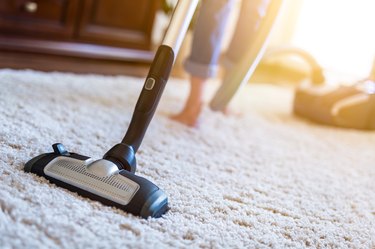 Woman using a vacuum while cleaning carpet in the house.