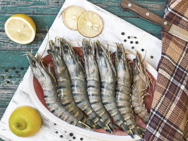 Fresh raw tiger prawns and spices on wooden table