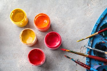 Jars with paints and brushes on table