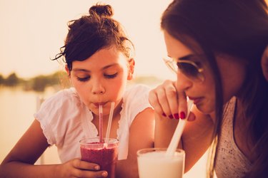 Madre e hija bebiendo jugo en café