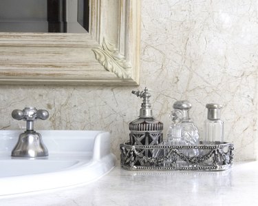 A silver tray with a collection of antique perfume bottles over a bathroom counter. Still life.