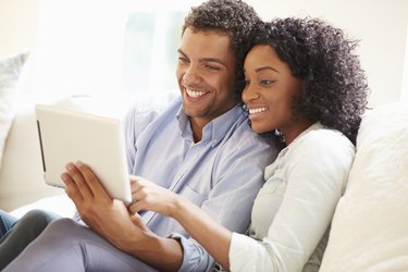 Pareja joven sentada en el sofá usando tableta digital