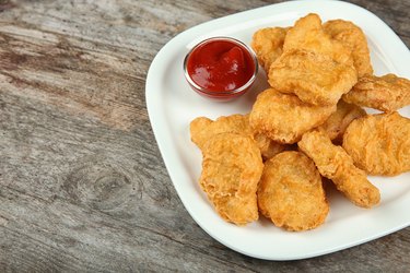 Plate with tasty chicken nuggets and sauce on table